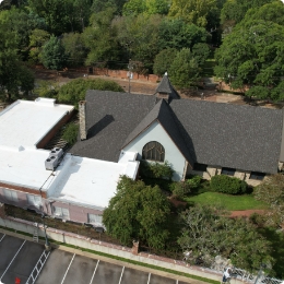 A large, elegant brick home with a gray shingle roof, multiple gables, and a small cupola on top.
